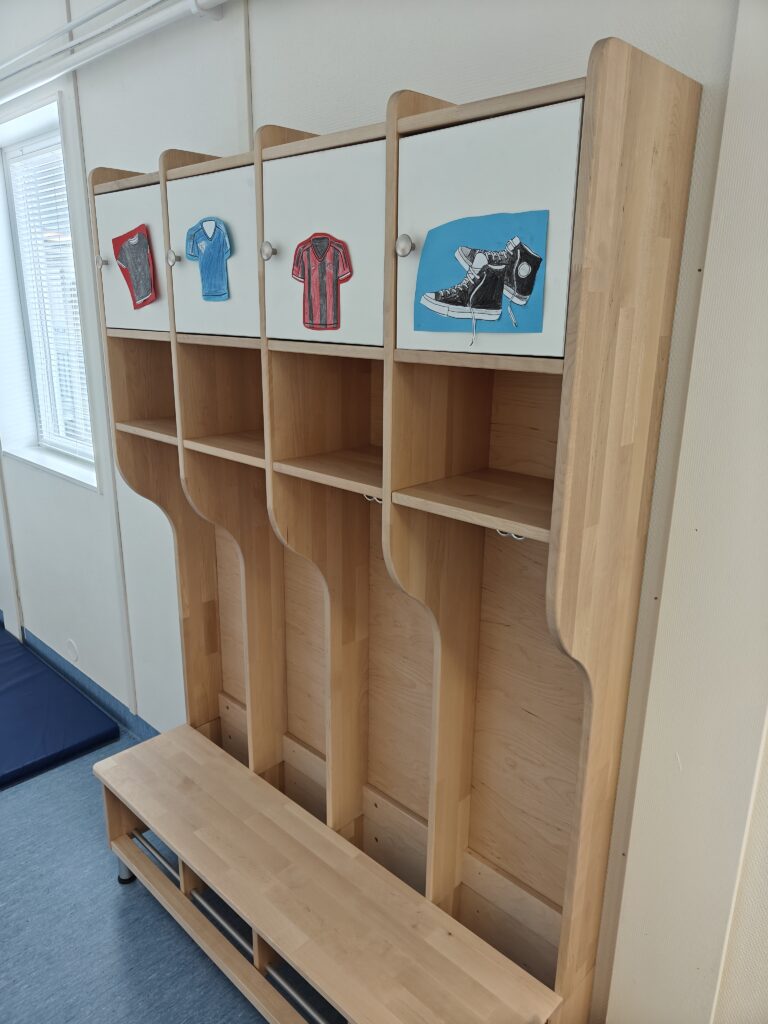 Naulakko koulun käytävällä, jossa on myös pieni lokero ja kaappi oppilaan tavaroille.